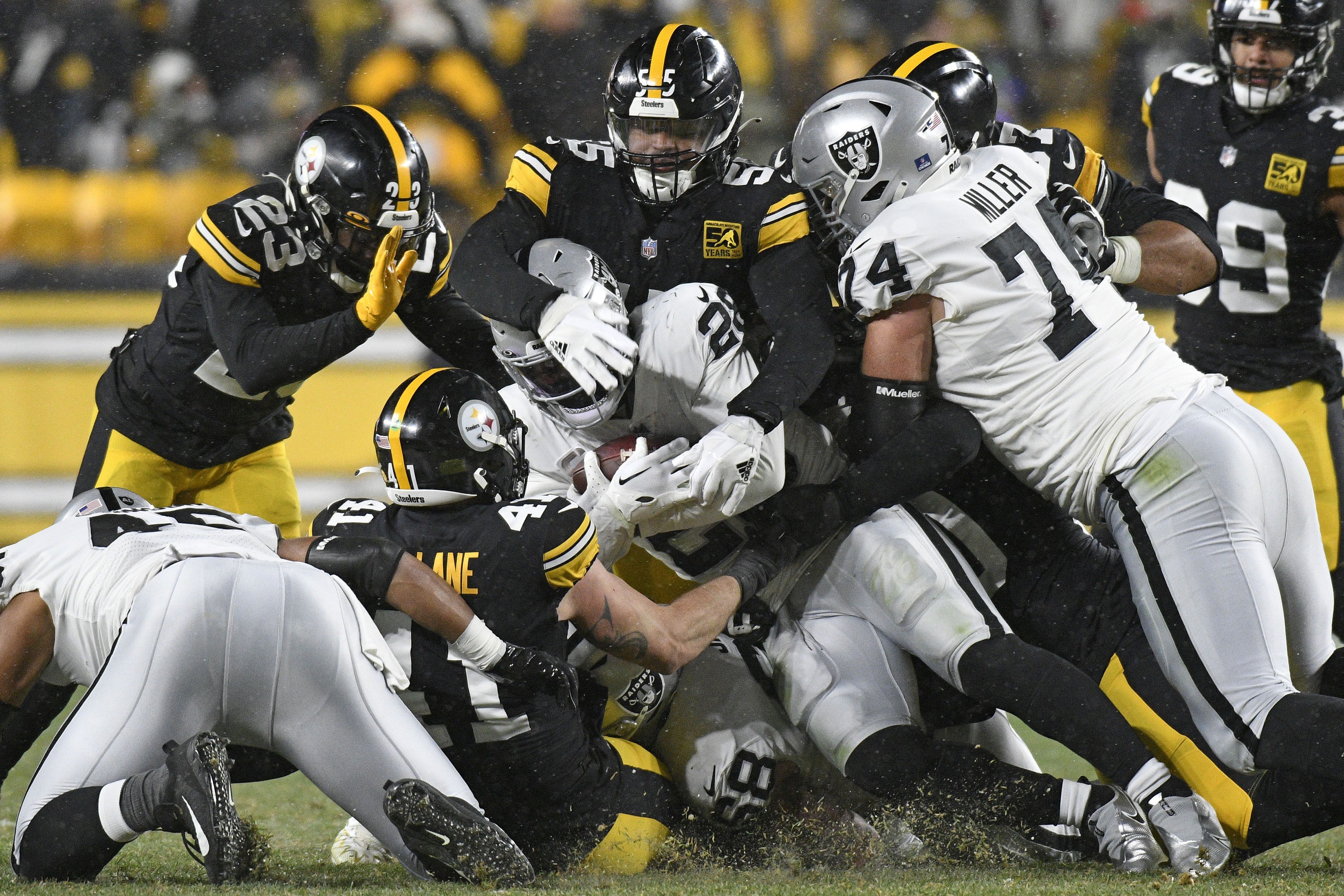 Pittsburgh Steelers defensive tackle Cameron Heyward (97) carries a flag  with Franco Harris number 32 on to the field before the start of the game  against the Las Vegas Raiders at Acrisure